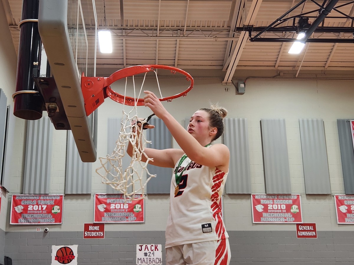 Loudonville's Corri Vermilya cuts down the net after the Redbirds won the Division IV district title over Mogadore on March 2, 2024